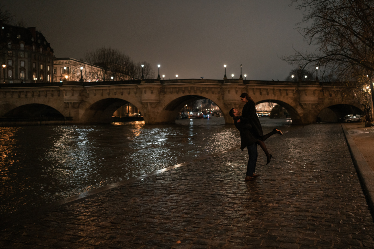 man lifts fiancee along the seine river in paris france