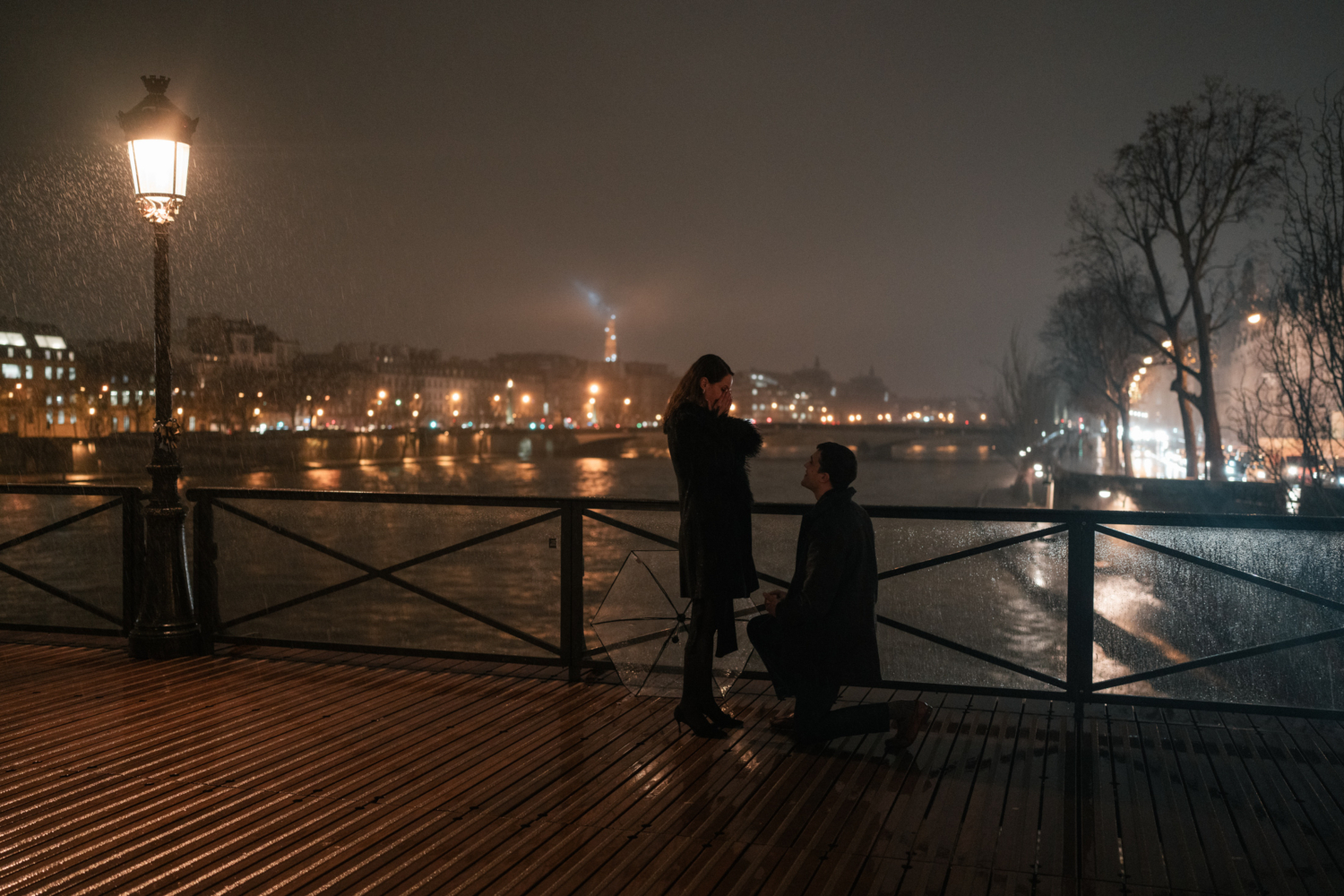 woman holds her hands in her face after man proposes on bridge in paris