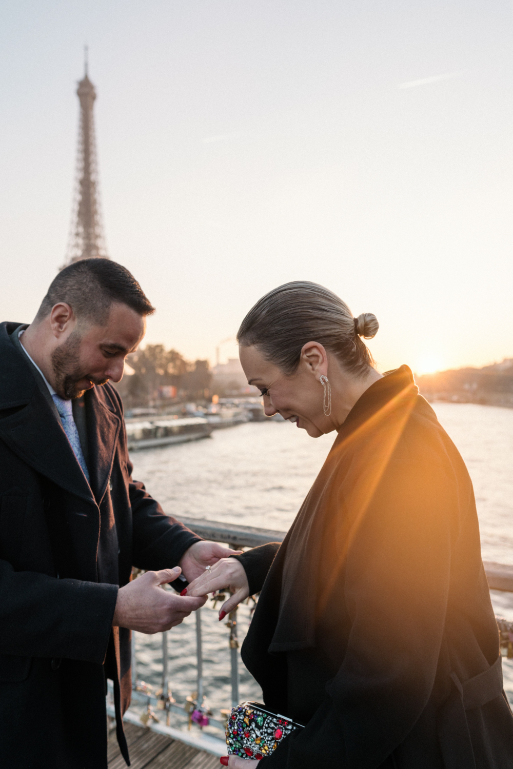 man presents woman engagement ring at sunset in paris