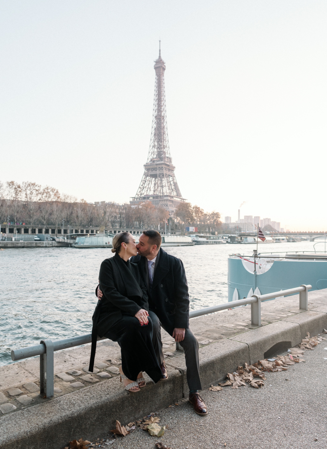 newly engaged couple kiss along the banks of the seine river in paris