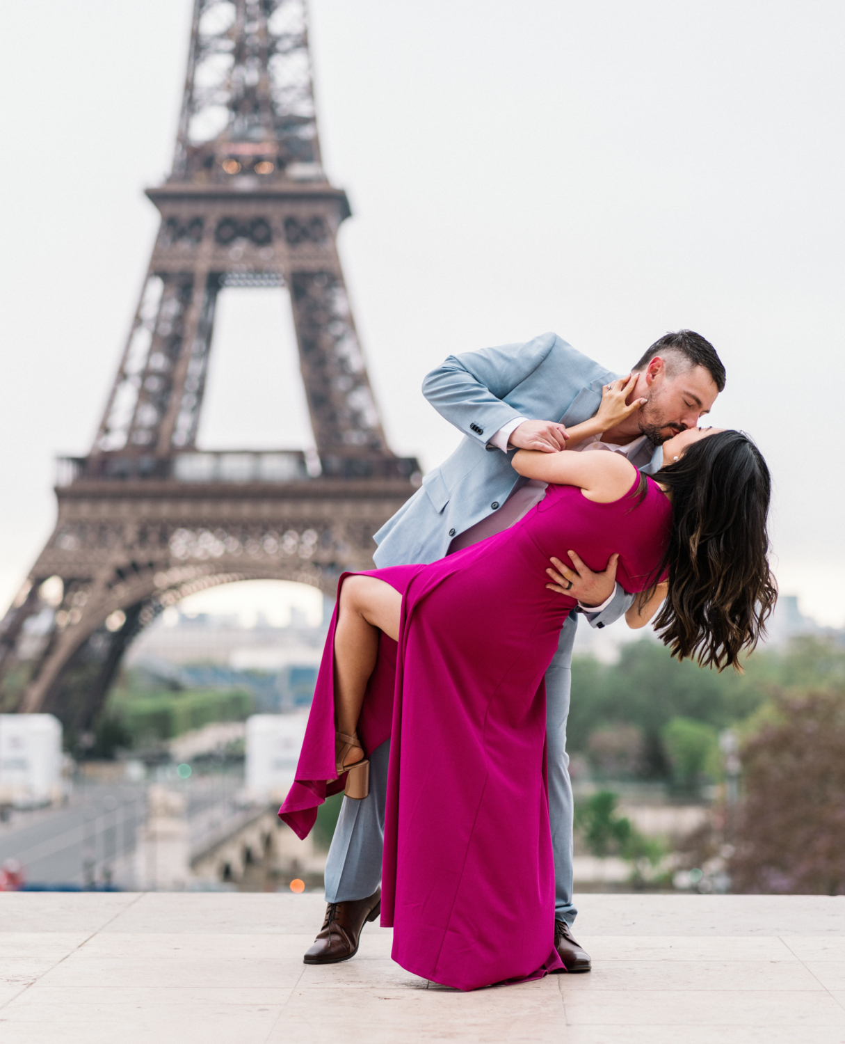 man tips woman and kisses her with eiffel tower in background