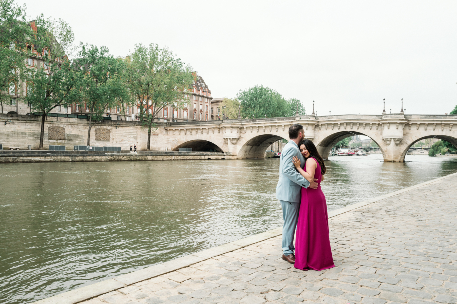 married couple embrace next to the seine river in paris