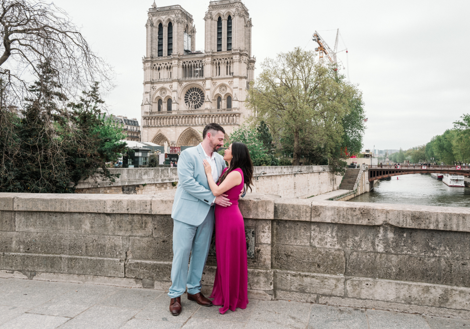 beautiful couple hold each other in front of notre dame cathedral in paris