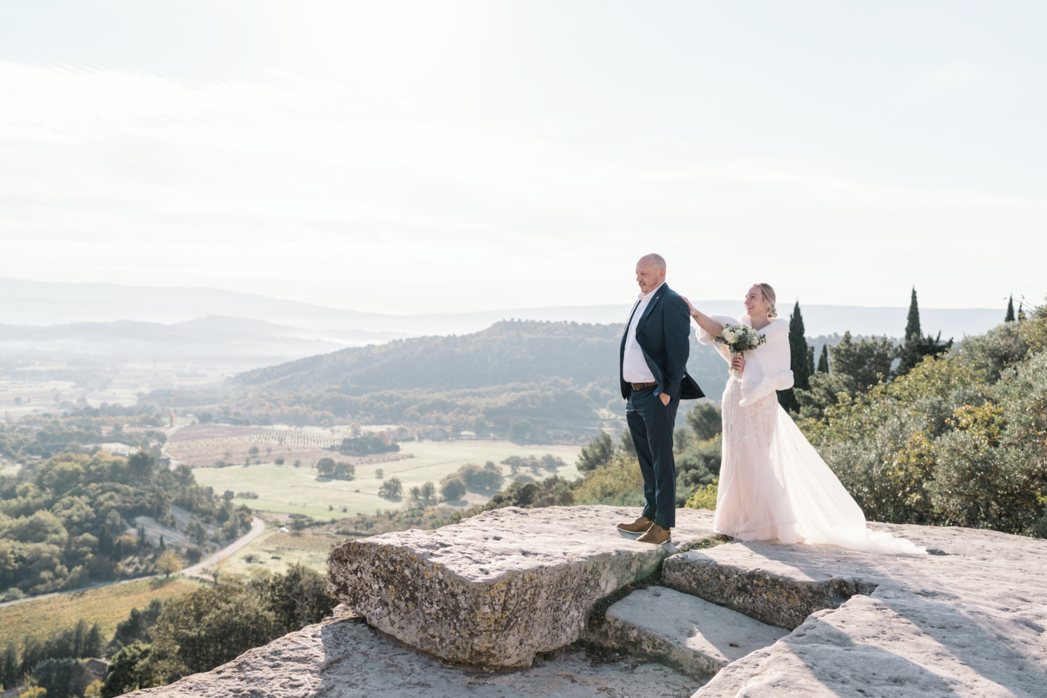 bride taps on the back of groom's shoulder on their wedding day in gordes france provence