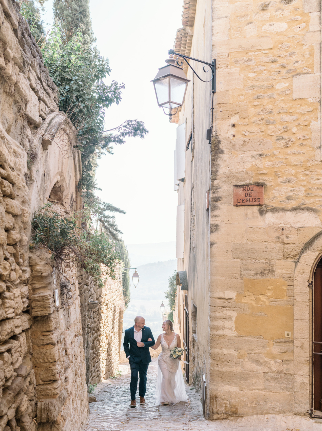 bride and groom walk the ancient streets in gordes france provence