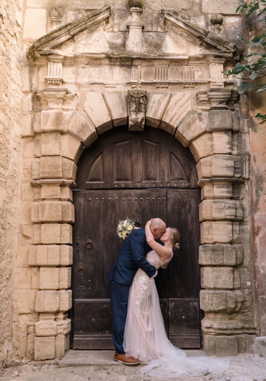 bride and groom passionately kiss in front of brown door in gordes france provence