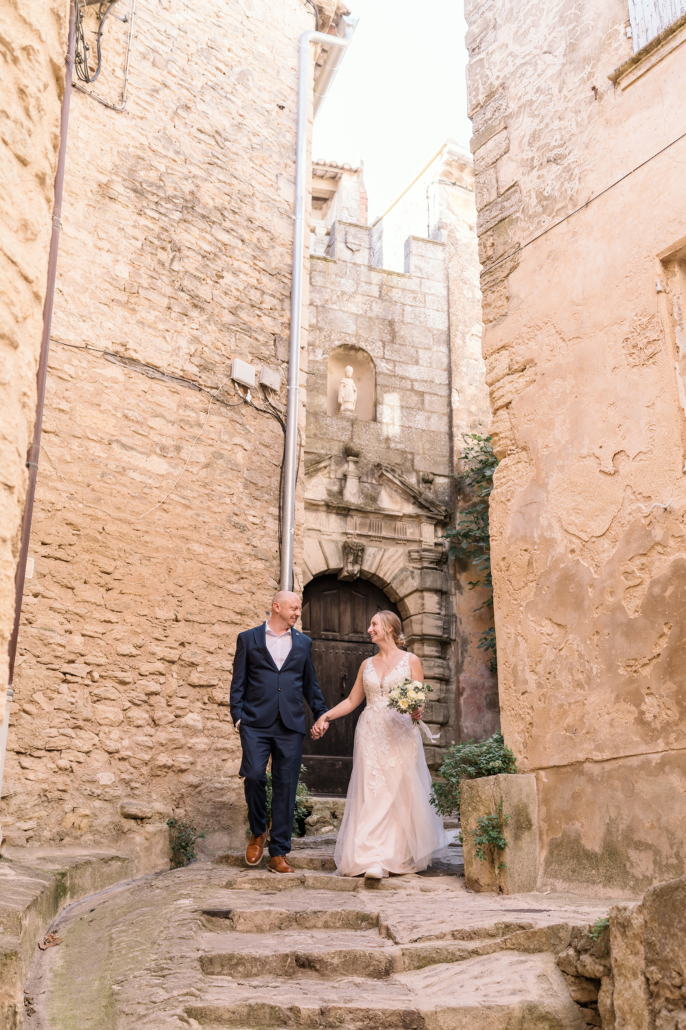 bride and groom walk down ancient staircase in gordes france