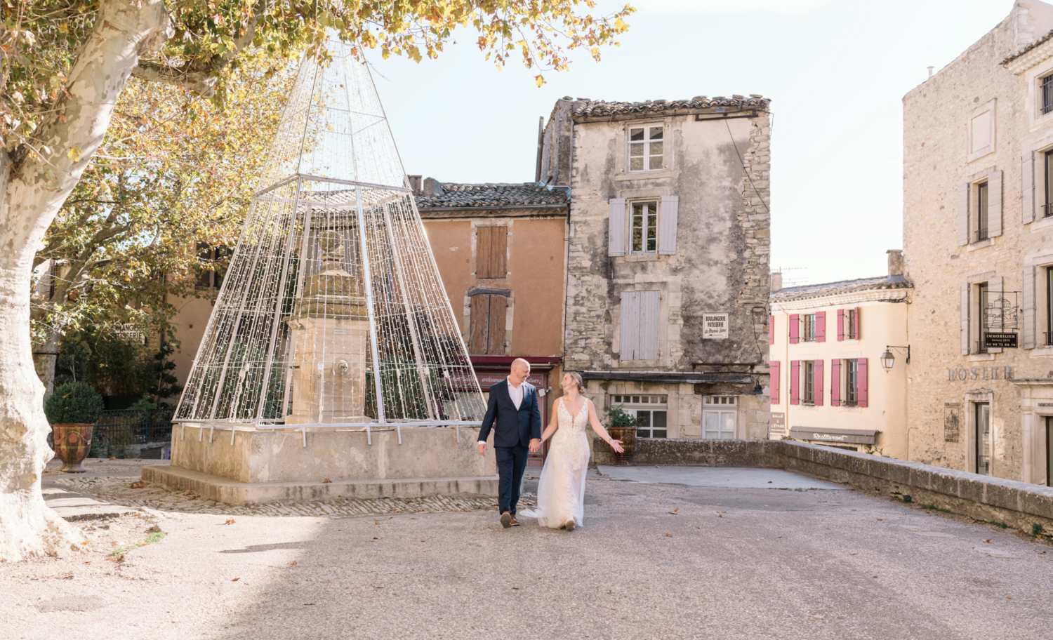 bride and groom walk hand in hand in gordes france