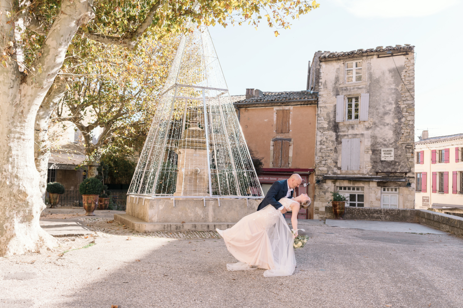 groom dips bride in front of old fountain in gordes france