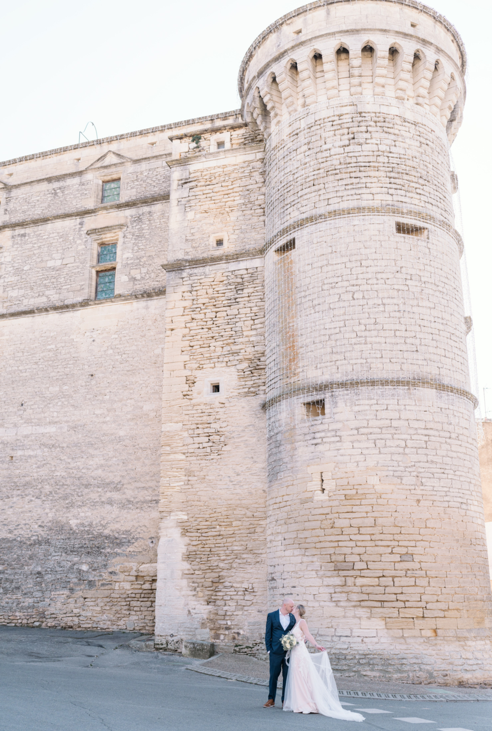 bride and groom kiss in the shadow of a castle in gordes france