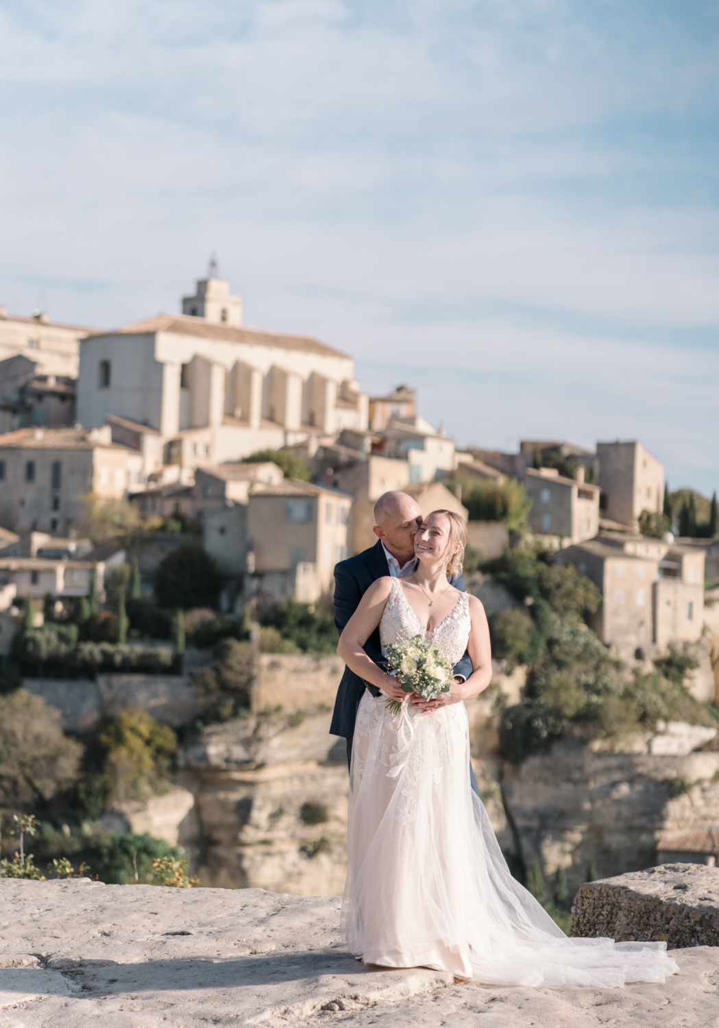 groom kisses bride on face during their wedding in gordes france