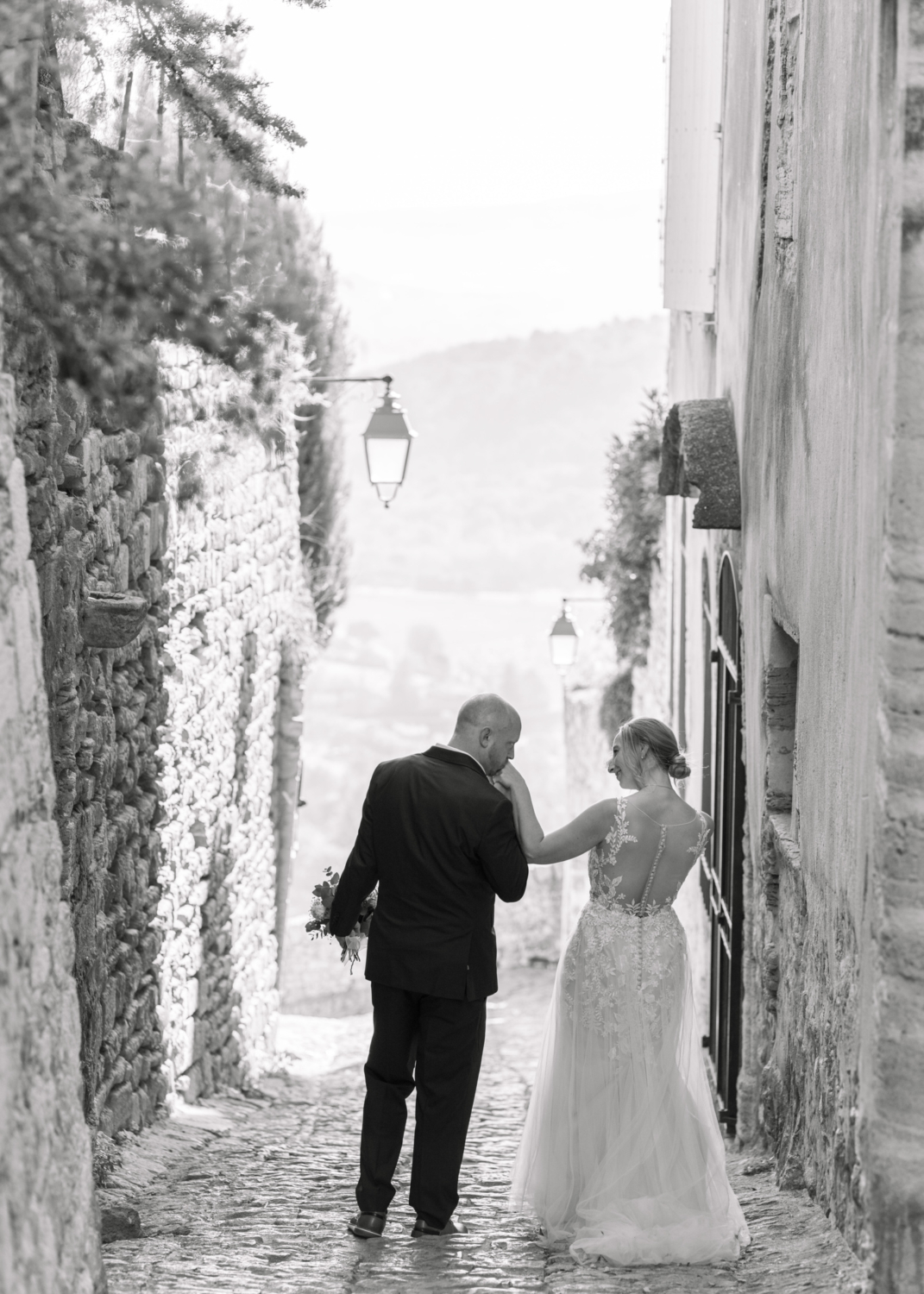 groom kisses bride's hand in gordes france on their wedding day