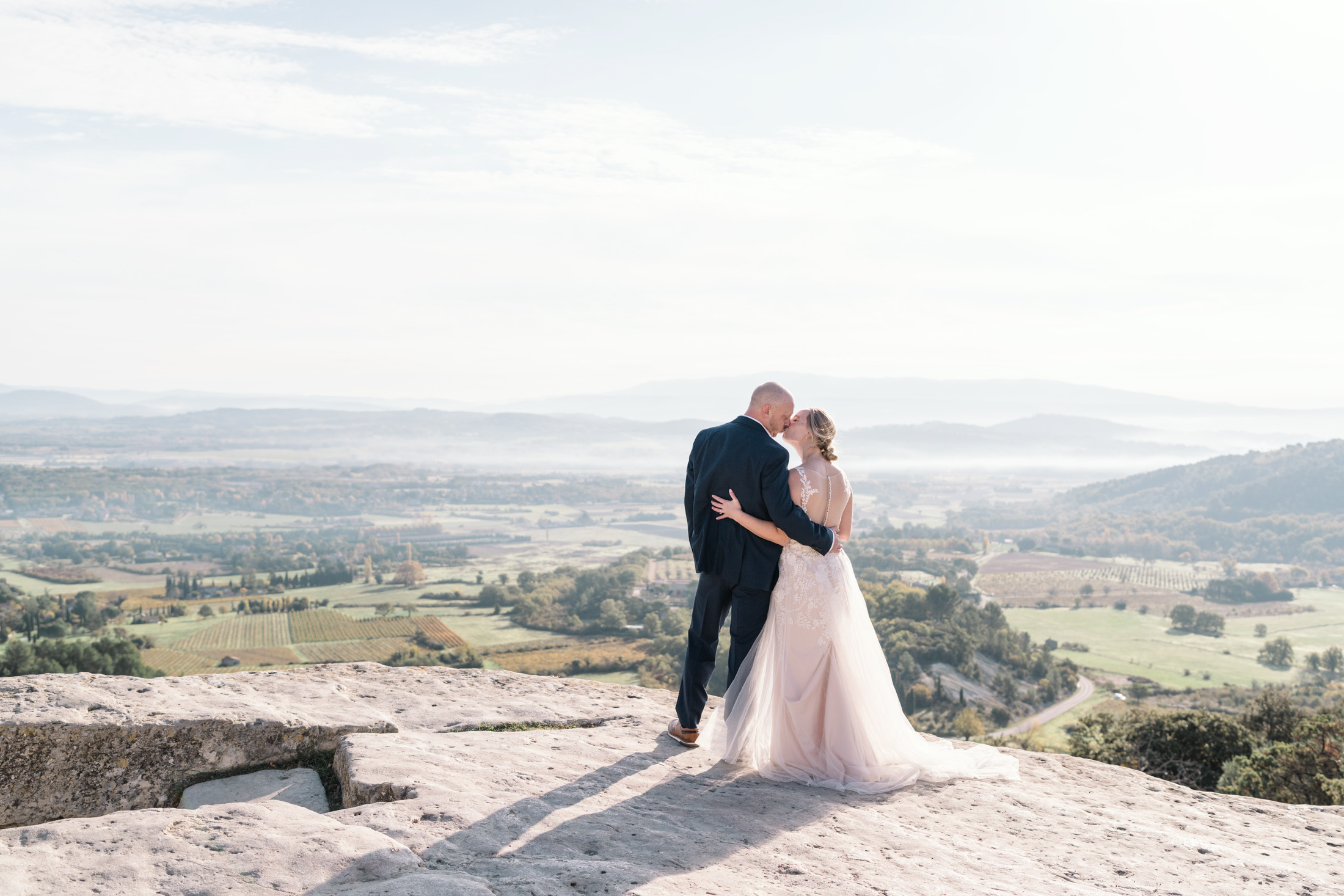 bride and groom kiss in gordes france provence with view of vineyards