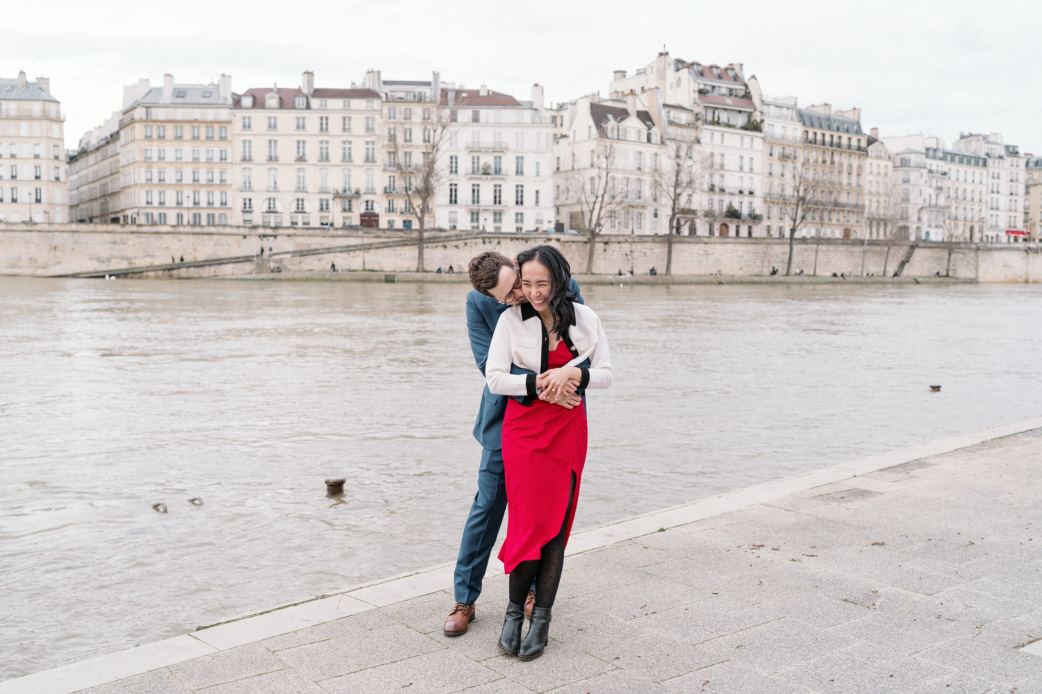 newly engaged couple laugn along the seine river in paris