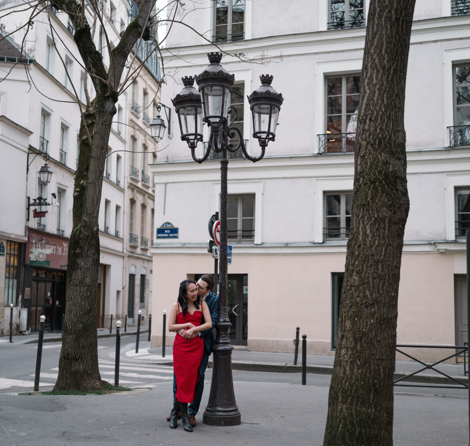 newly engaged couple embrace and kiss in cute parisian neighborhood