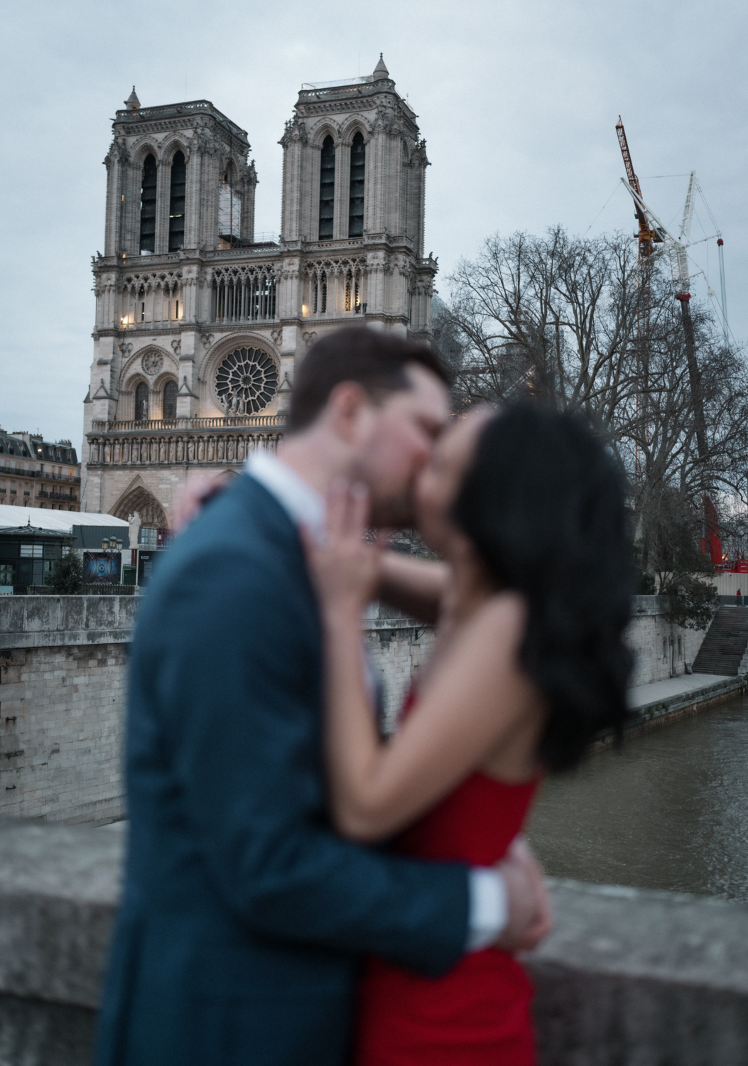 passionate couple kissing at dusk with notre dame cathedral in paris