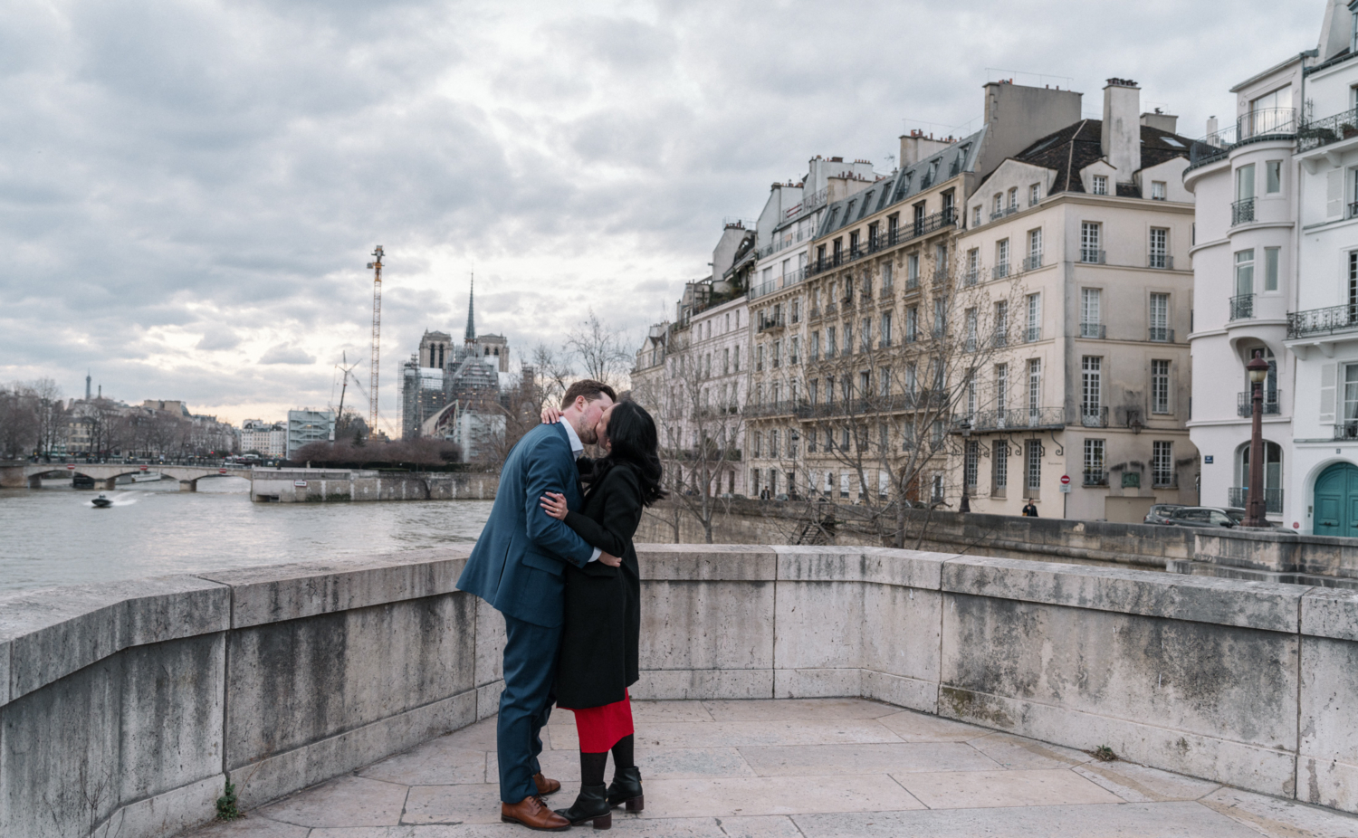 newly engaged couple kiss passionately on the pont de la tournelle