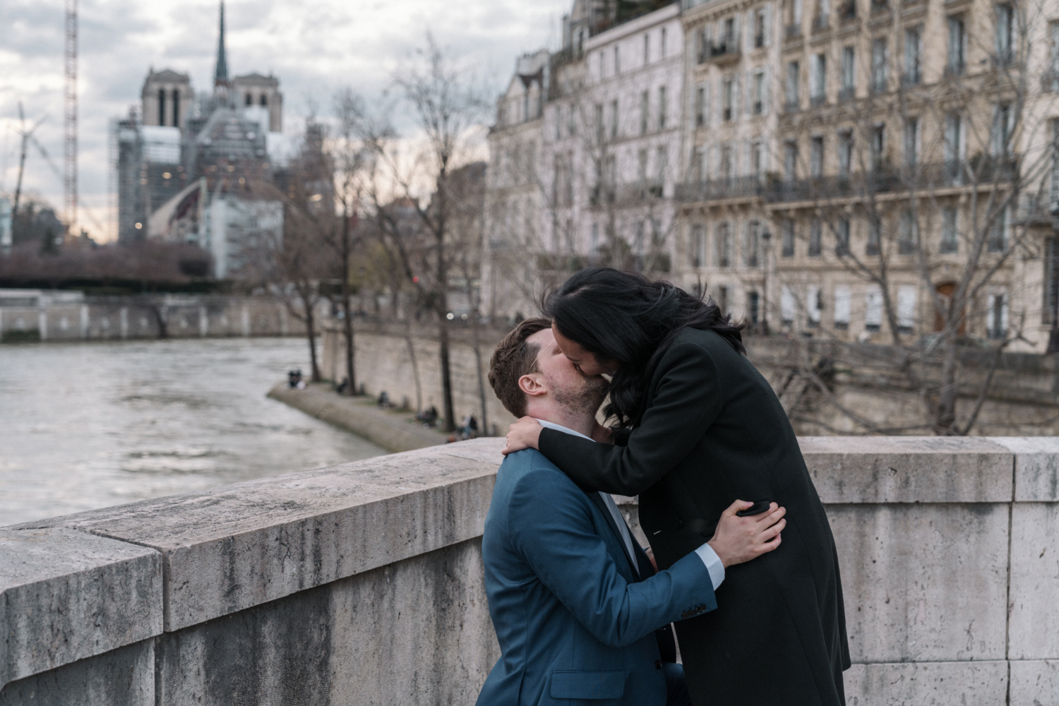 newly engaged couple kiss after their engagement on the pont de la tournelle