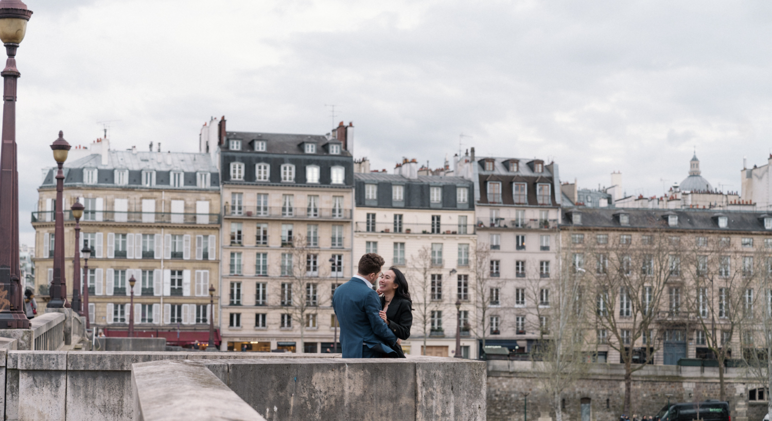 newly engaged couple embrace with view of charming paris neighborhood