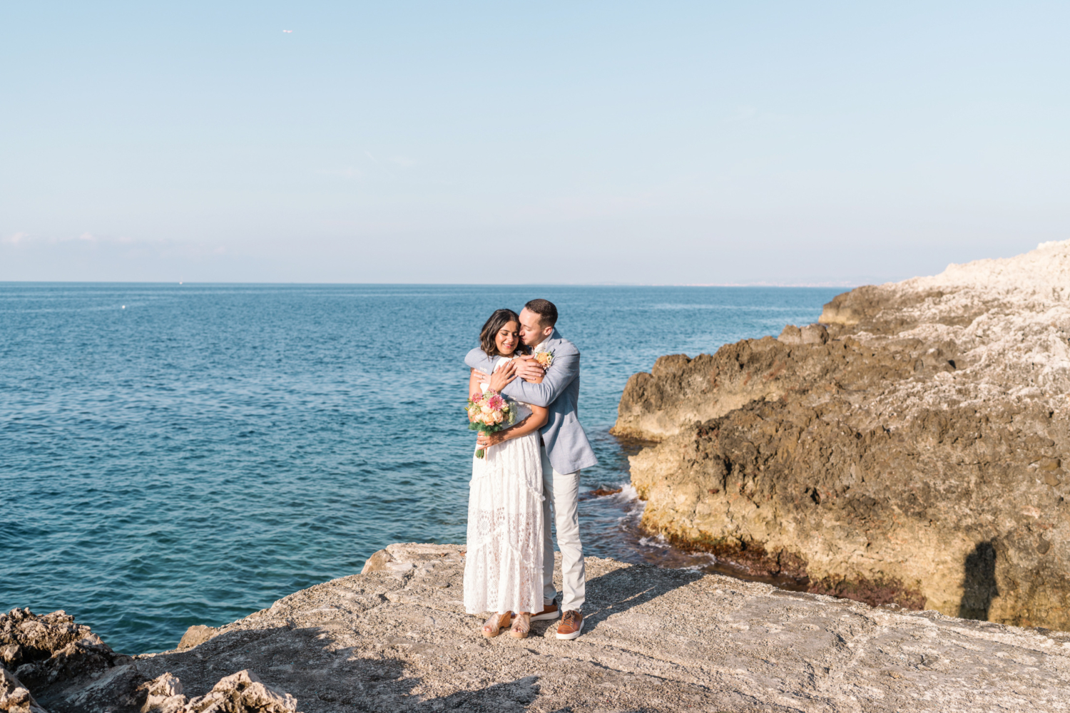 bride and groom embrace with a view of the sea in saint jean cap ferrat france on the french riviera