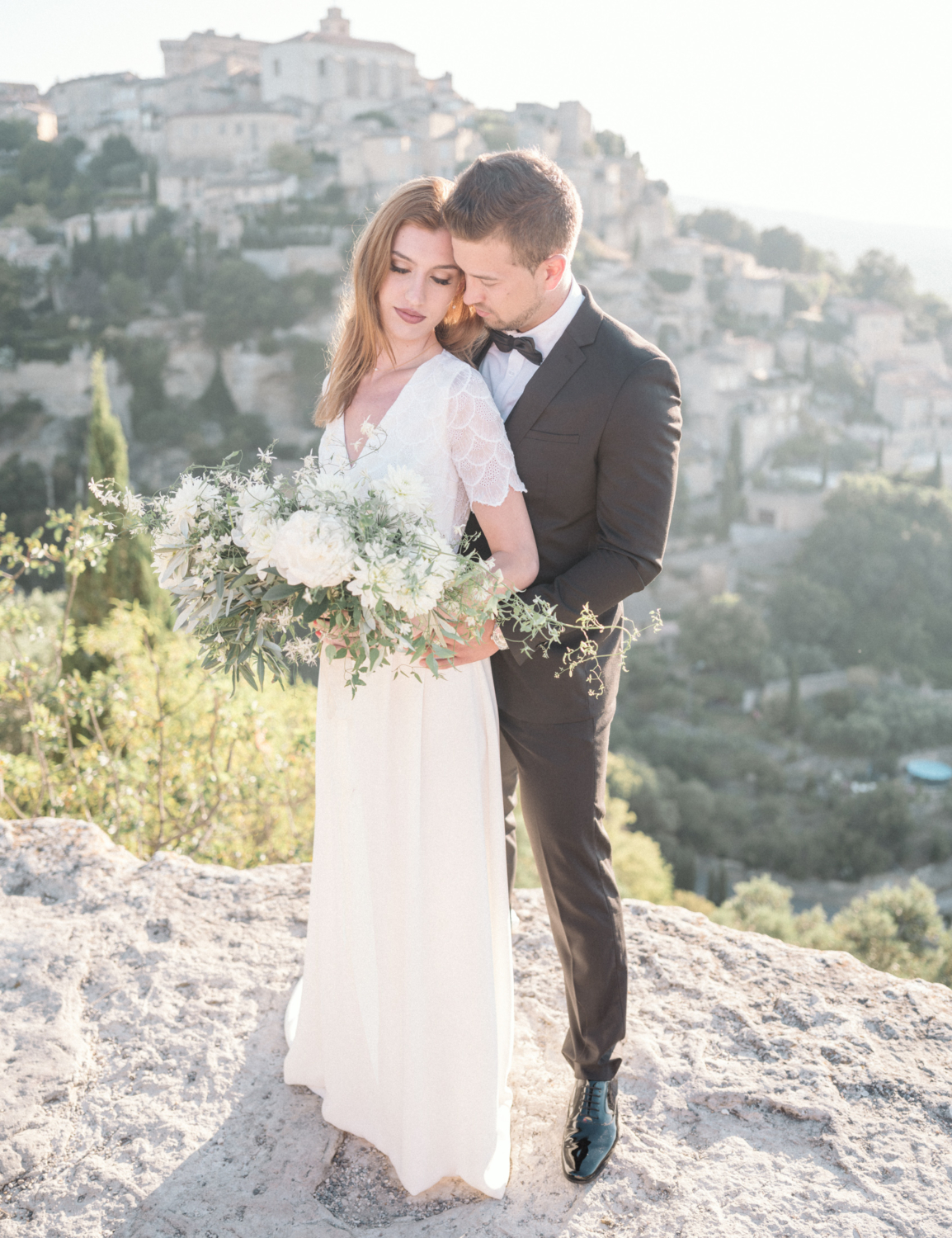 bride and groom embrace with beautiful view of gordes villages in france