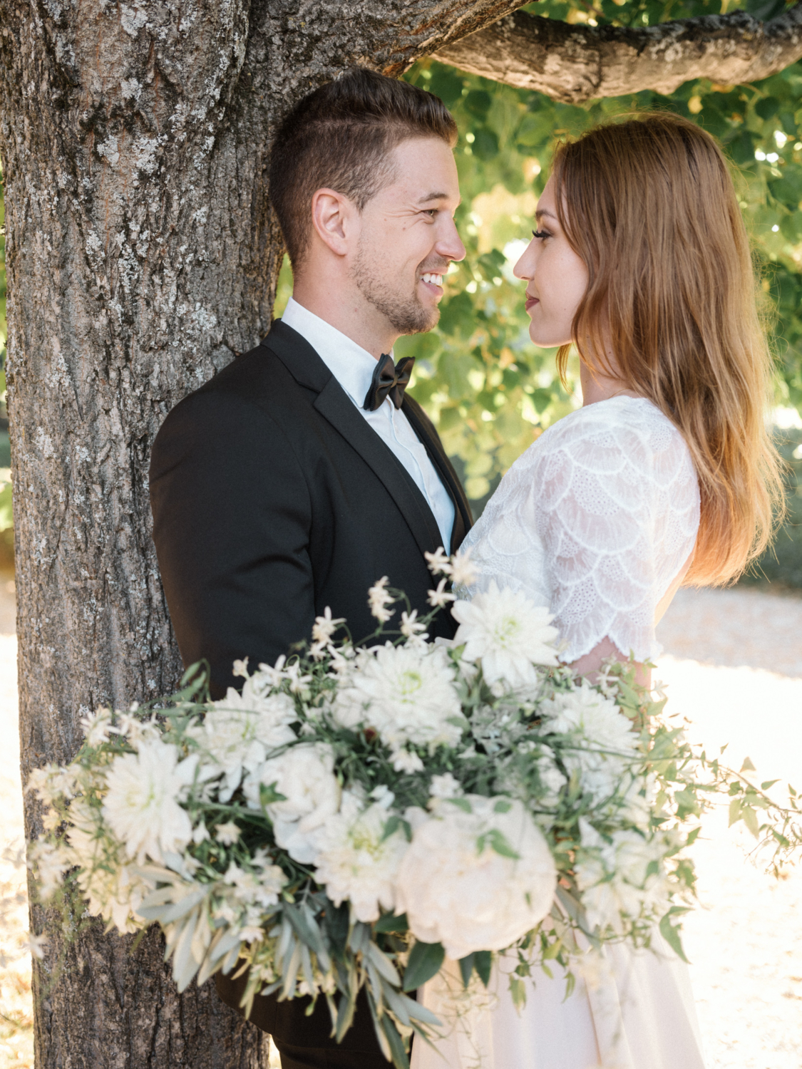 bride and groom pose next to tree in gordes france during their La Bastide de Gordes wedding