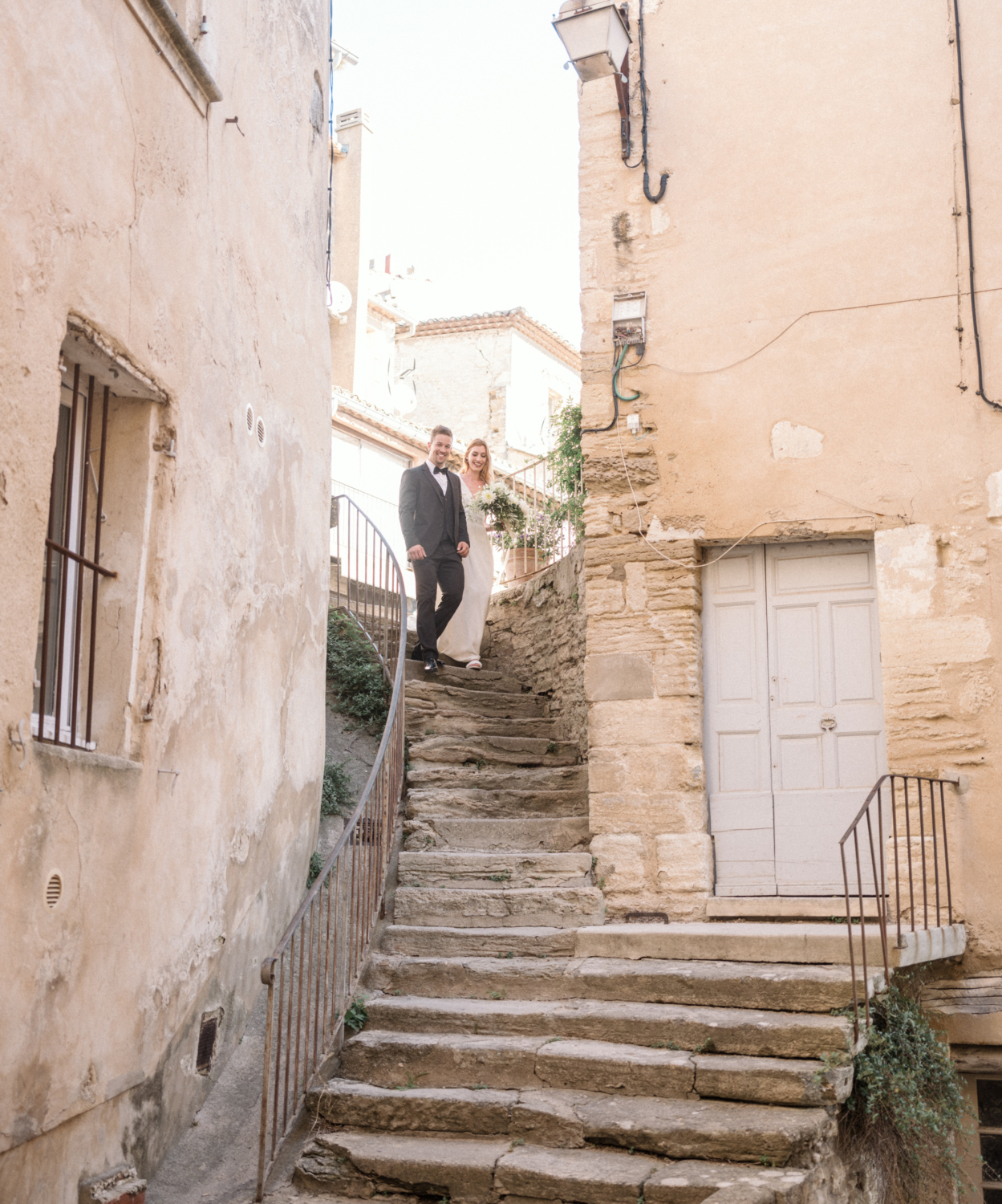 bride and groom smile as they walk down staircase in gordes france