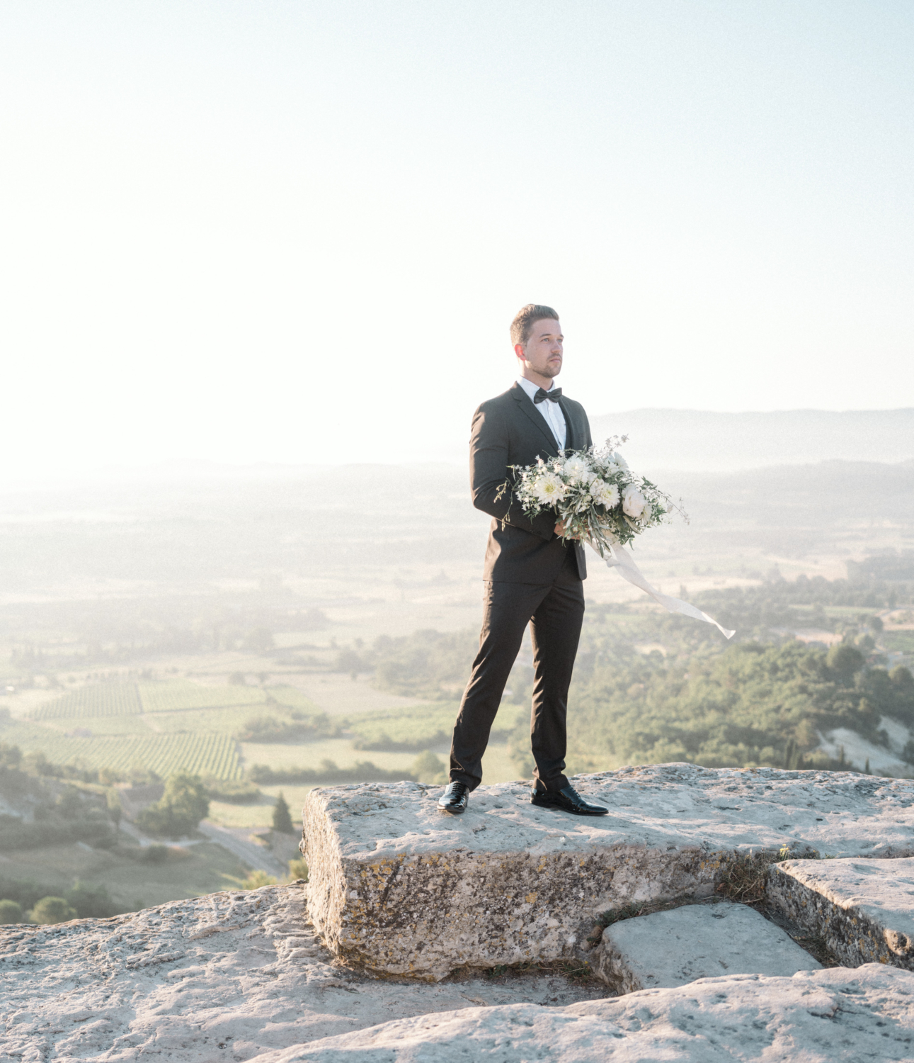 groom holds bouquet with gorgeous view in gordes france