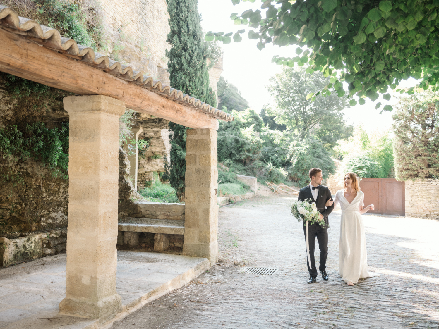 bride and groom walk and laugh in gordes provence france