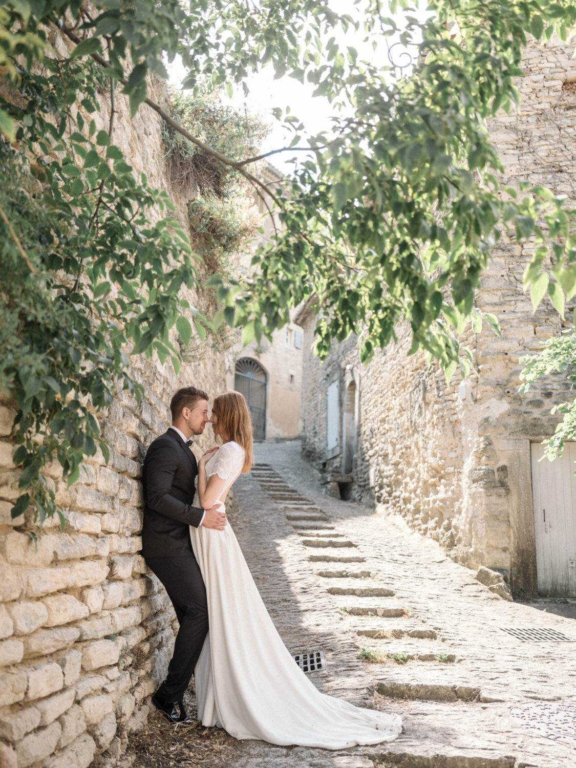 bride and groom are playful on stone wall in gordes provence france