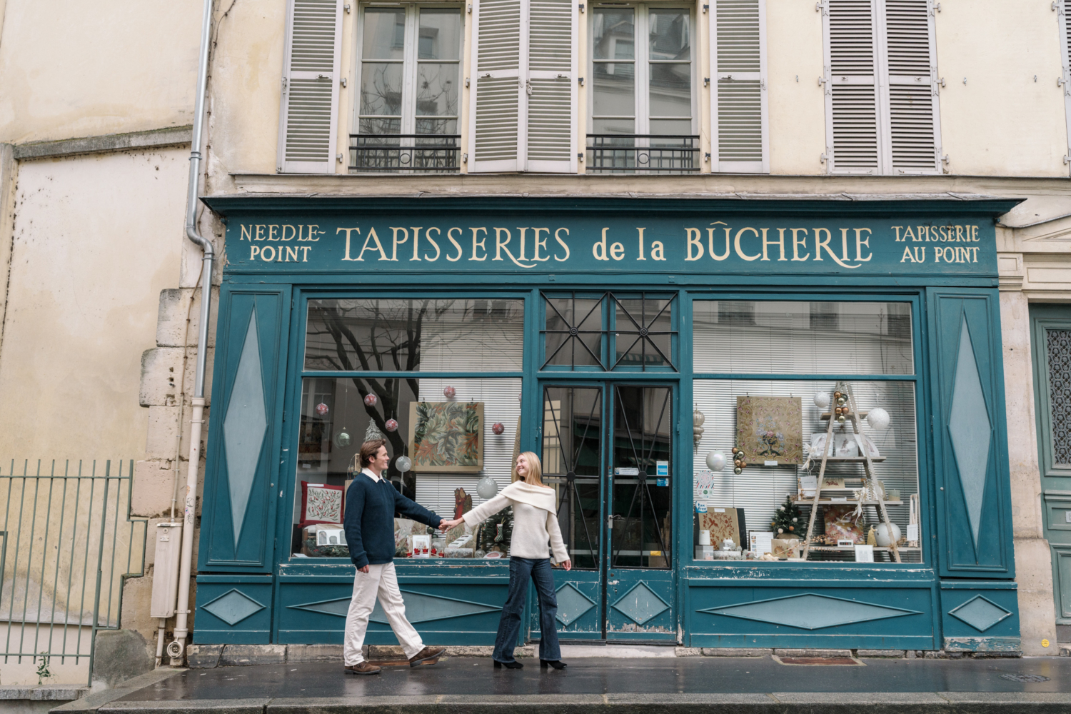 newly engaged couple walk in front of needlepoint shop in paris france