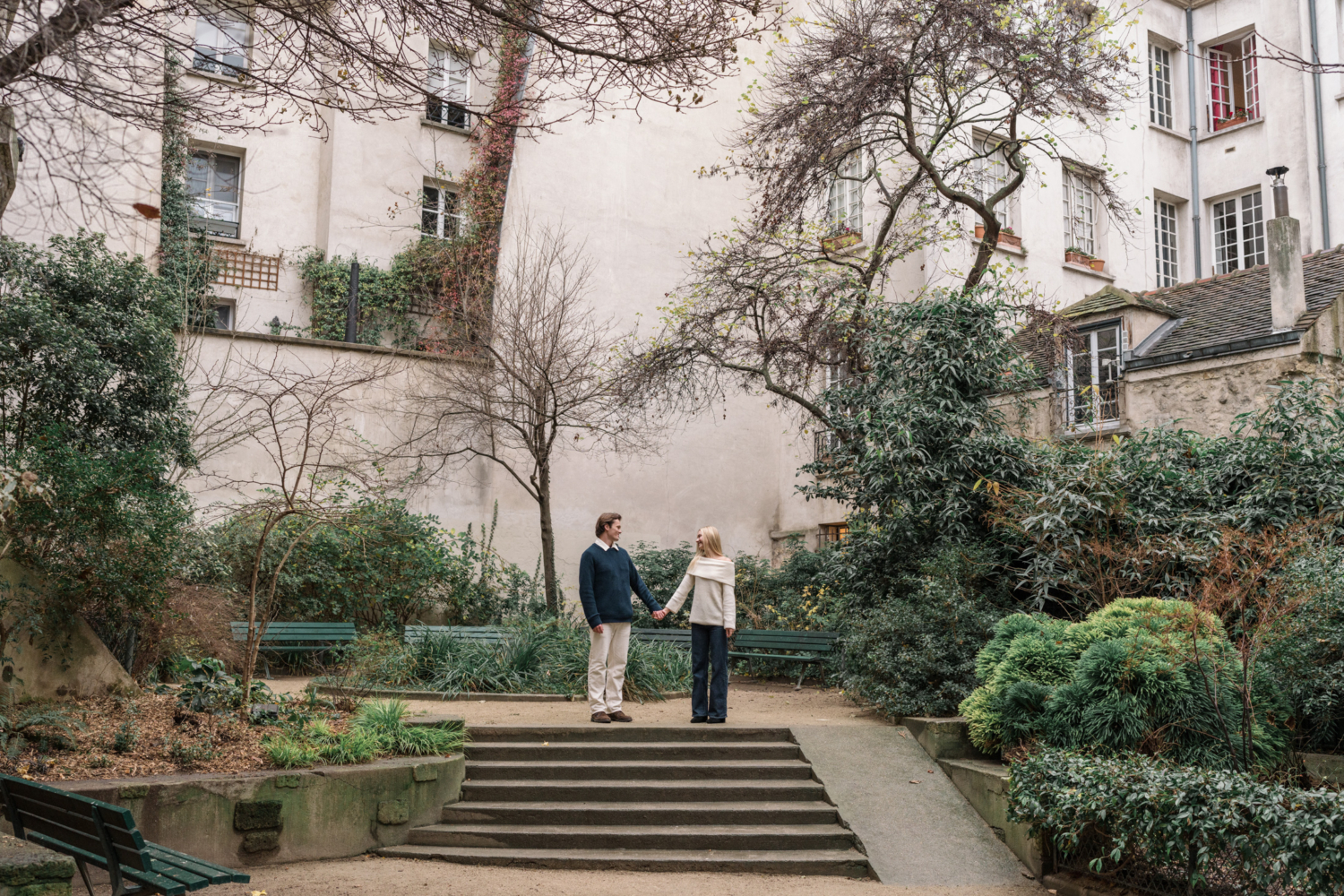 newly engaged couple hold hands in quaint parisian garden