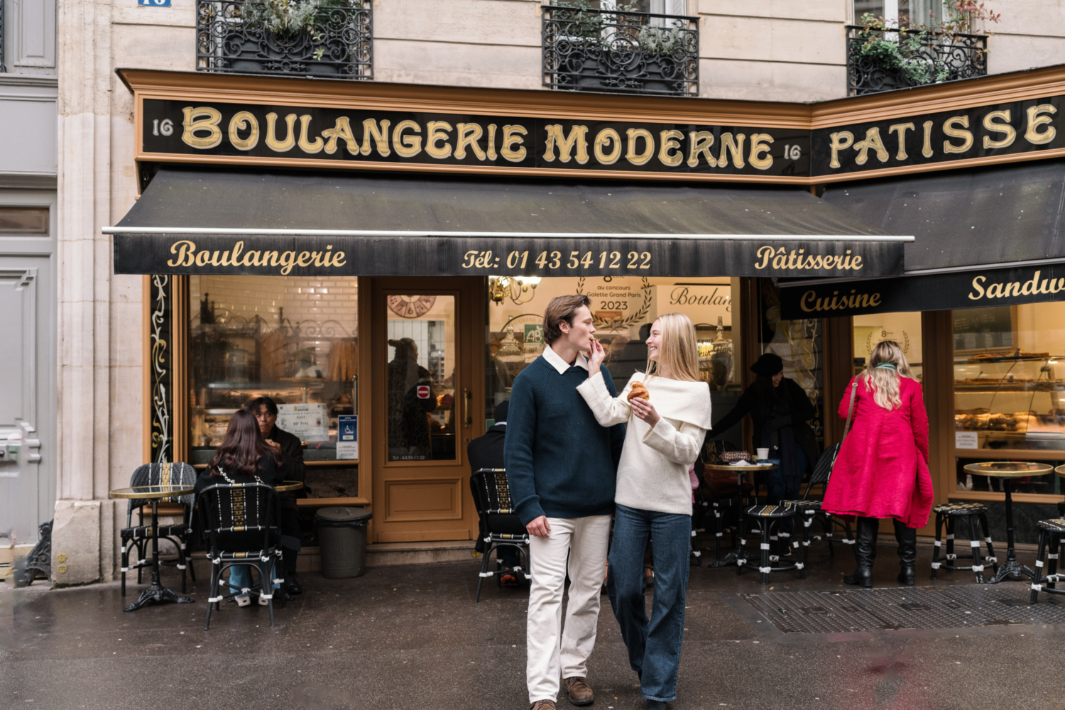 woman feeds croissant to man in front of boulangerie featured in emily in paris