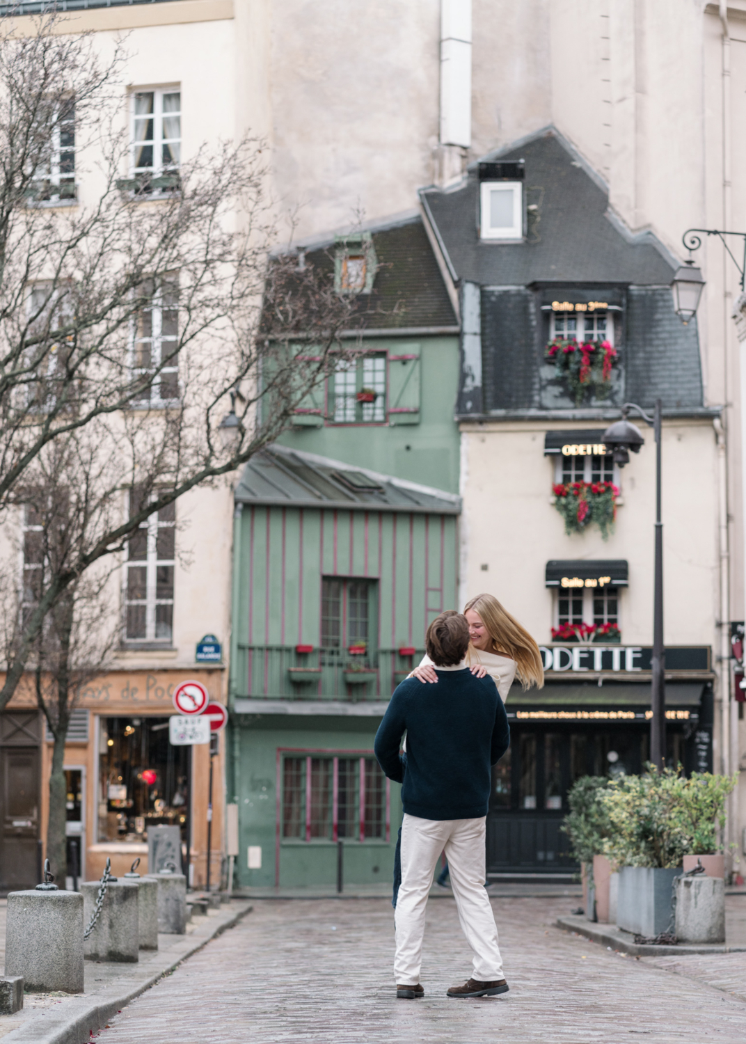 man twirls woman in charming parisian neighborhood with cobblestones