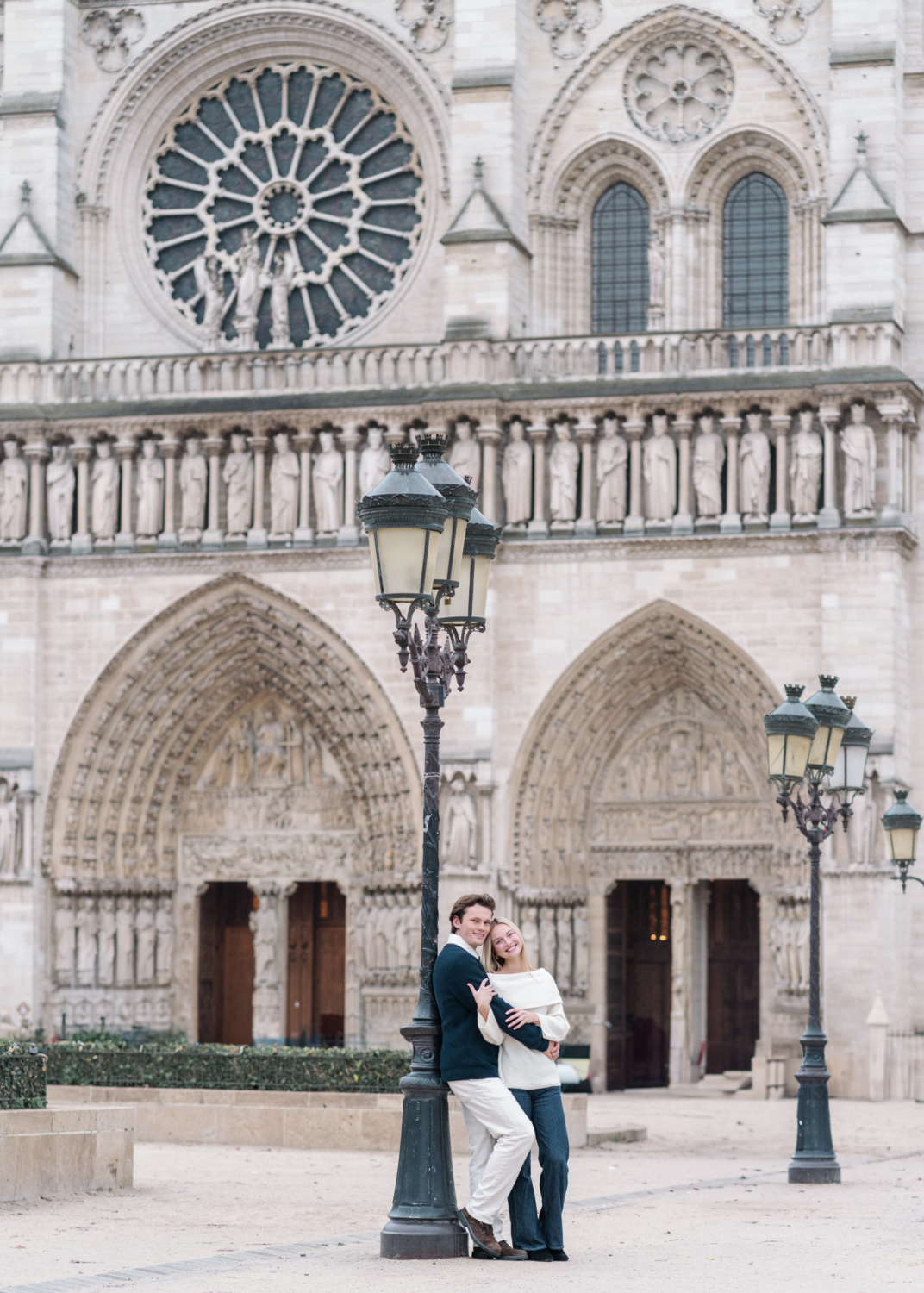 newly engaged couple smile in front of notre dame cathedral in paris france