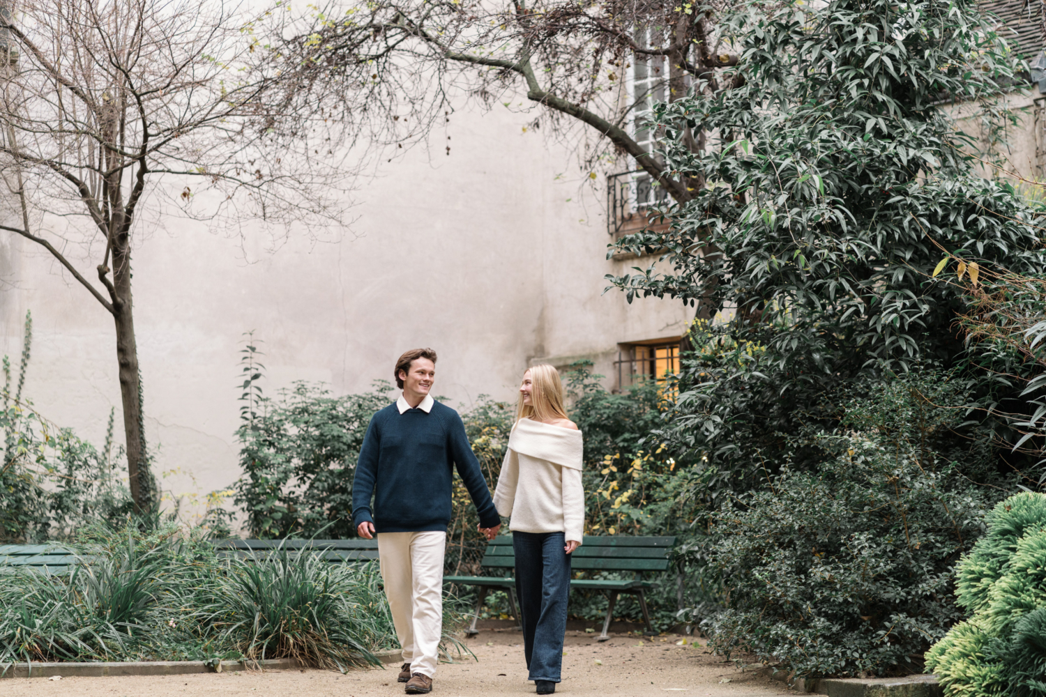 newly engaged couple walk hand in hand in paris garden