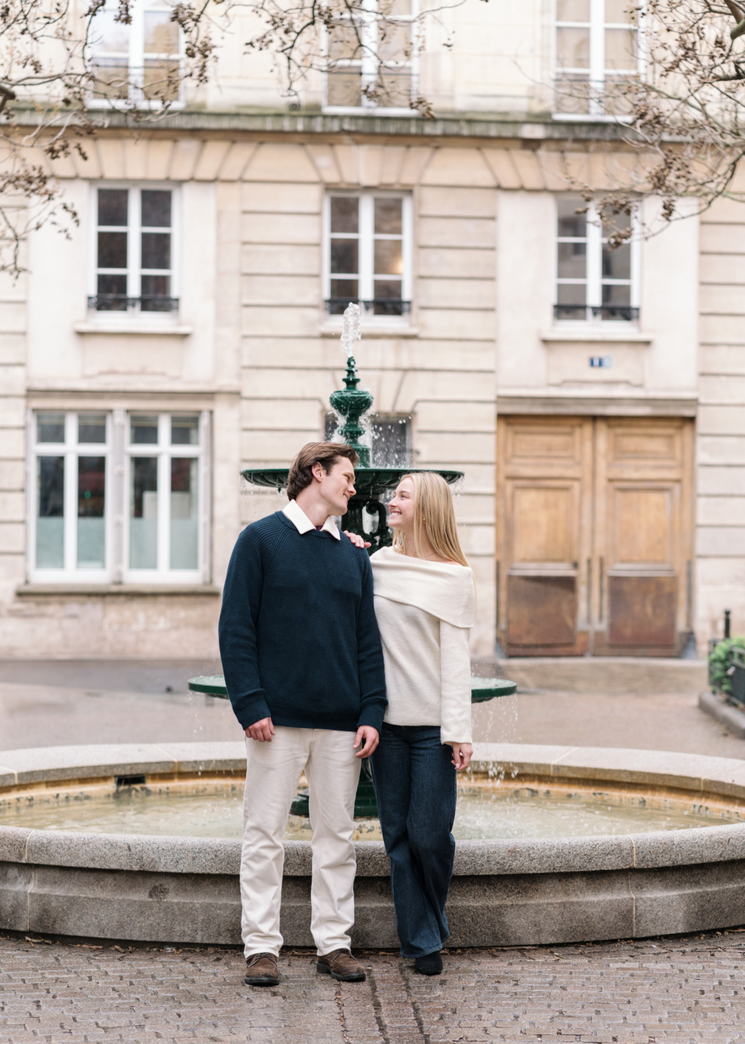 newly engaged couple pose in front of emily's apartment from emily in paris