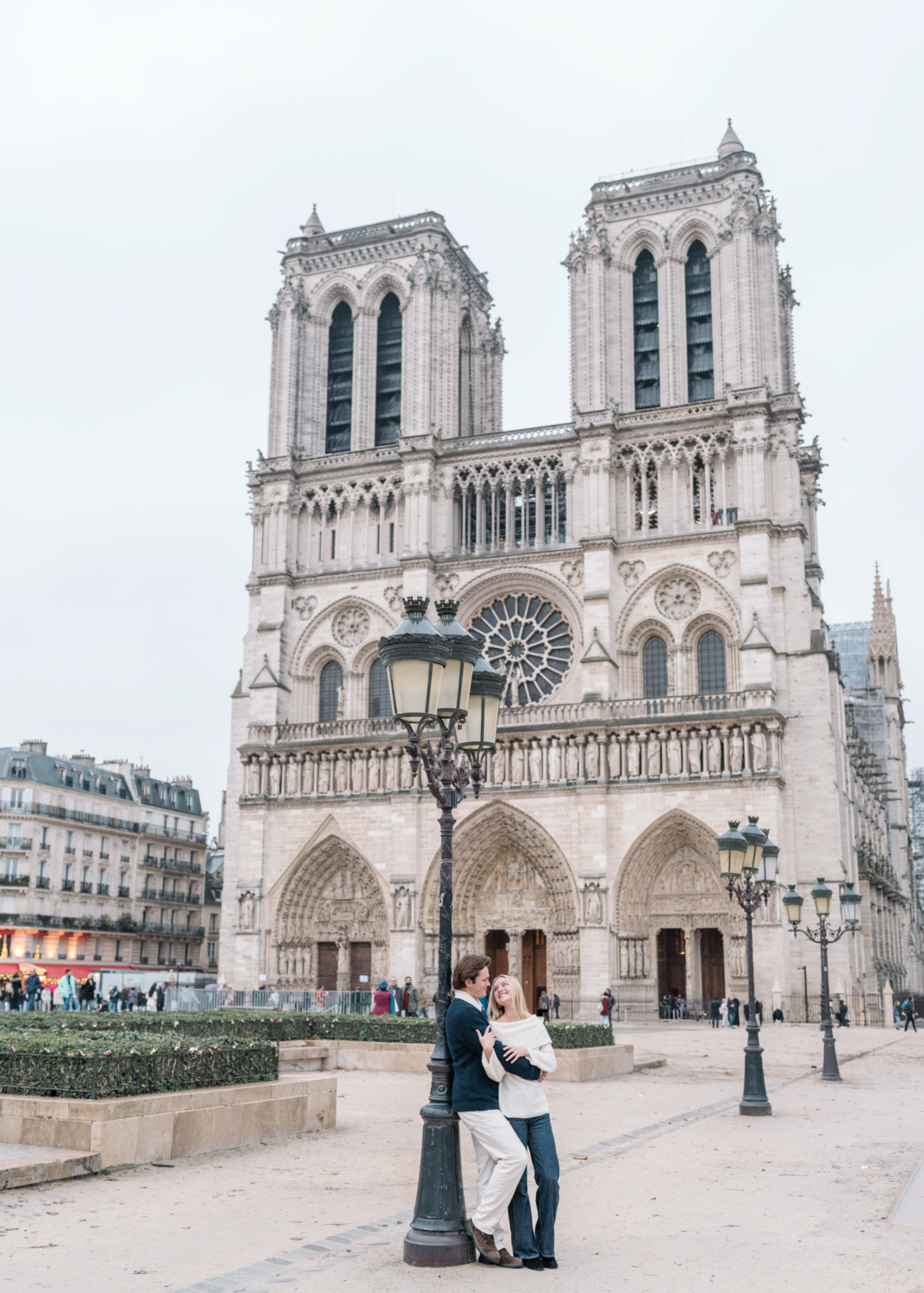 newly engaged couple pose in front of notre dame cathedral in paris