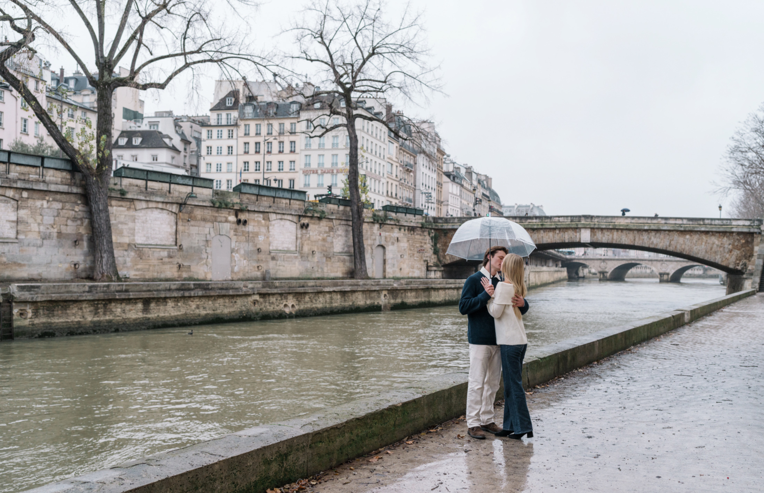 newly engaged couple kiss passionately along the banks of the seine river in paris