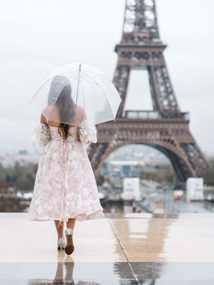 young woman walks with umbrella in the rain with a view of the eiffel tower