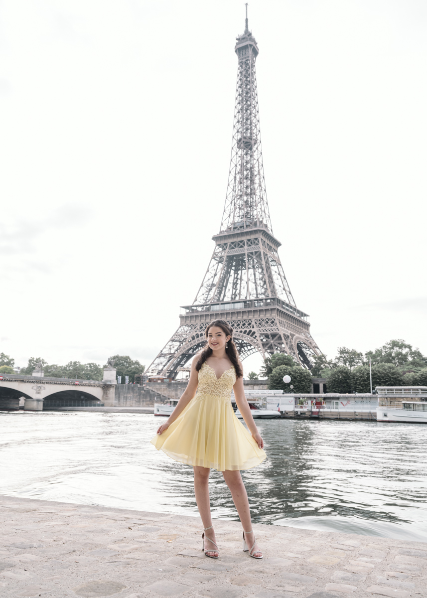 young girl in yellow dress poses in front of eiffel tower