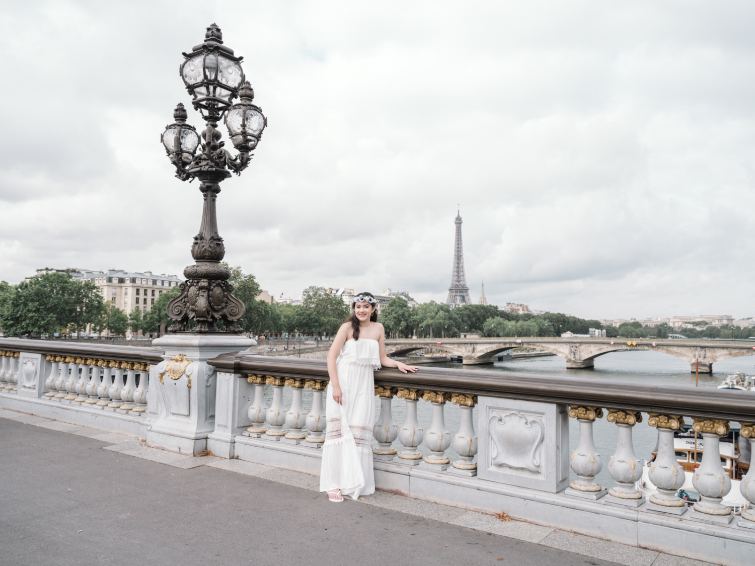 young woman in white dress smiles on the pont alexandre with view of the eiffel tower