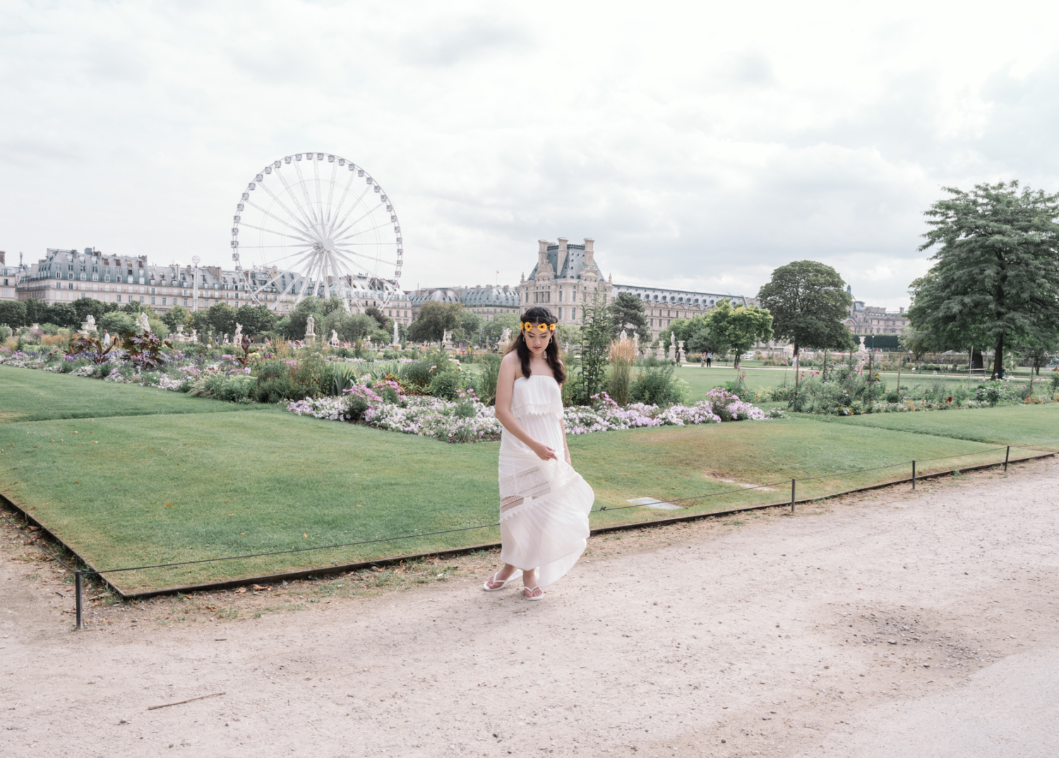 young woman in a white dress dances in the tuileries gardens in paris