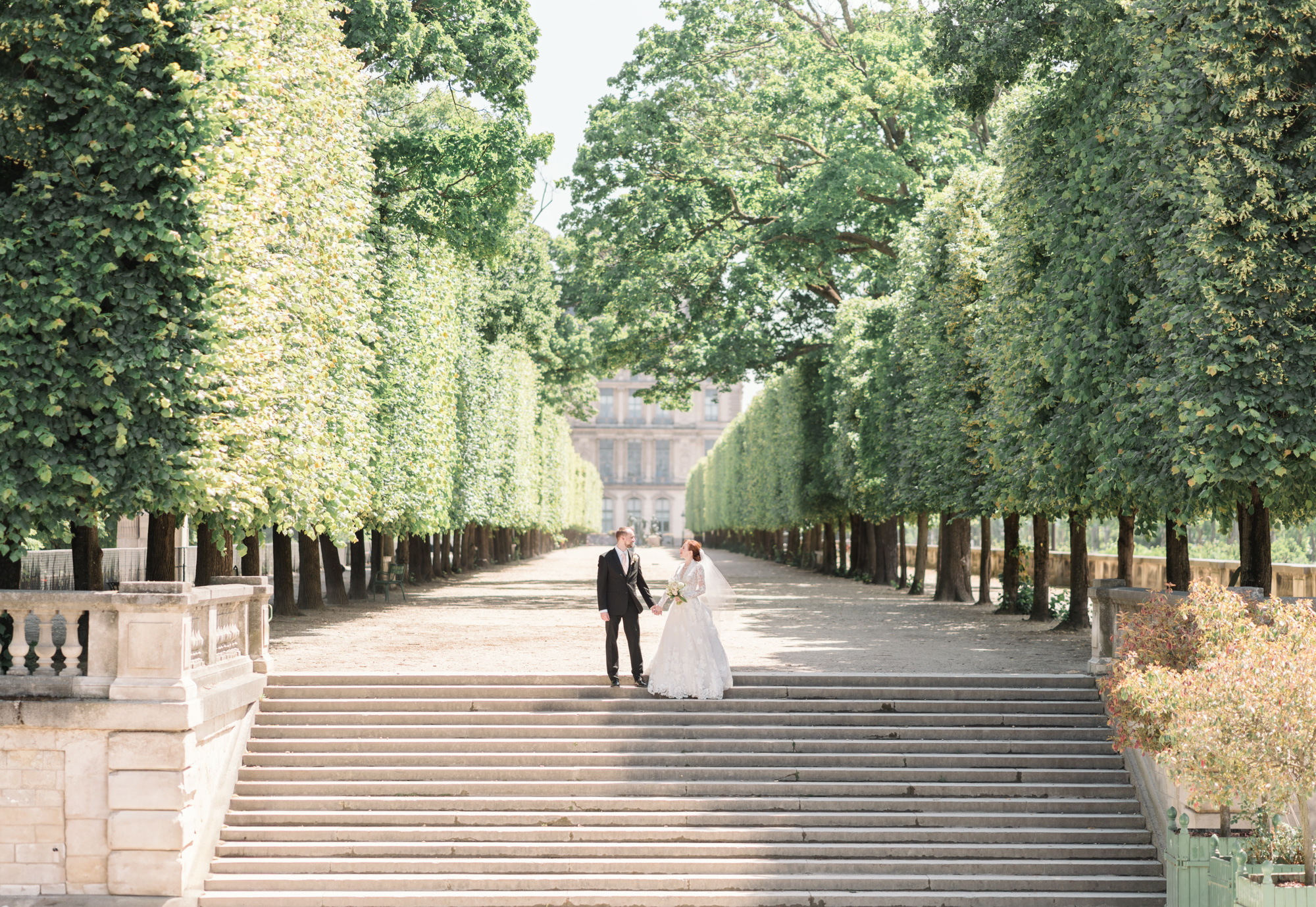 bride and groom pose on staircase in tuileries gardens in paris