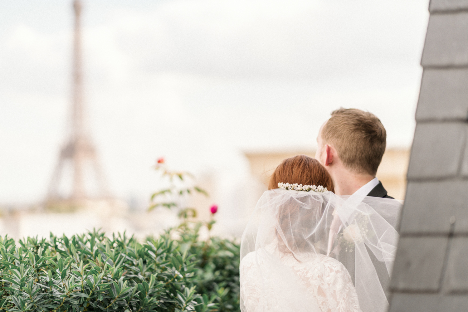 bride and groom look to the eiffel tower in paris