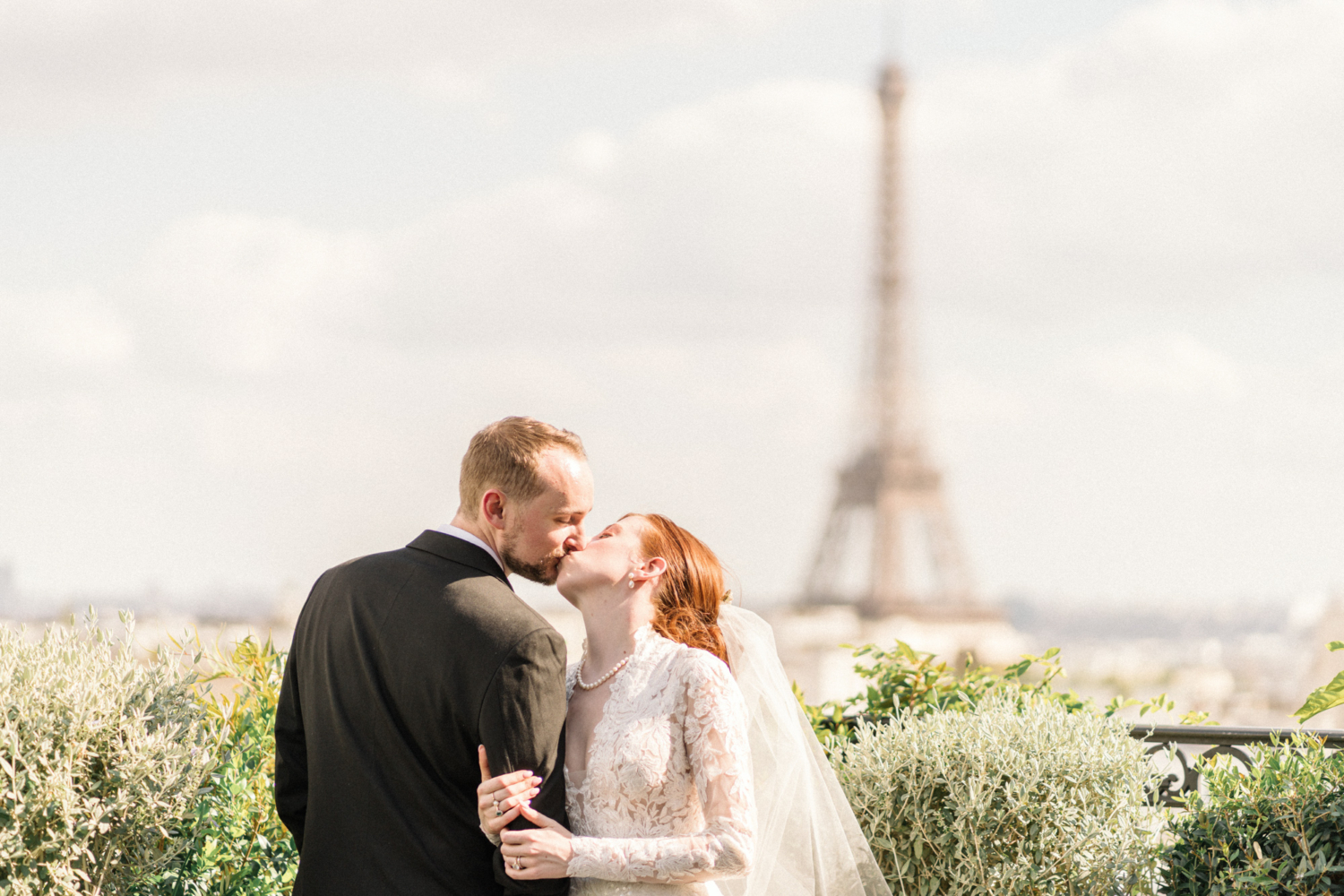 bride and groom kiss on terrace of peninsula hotel paris