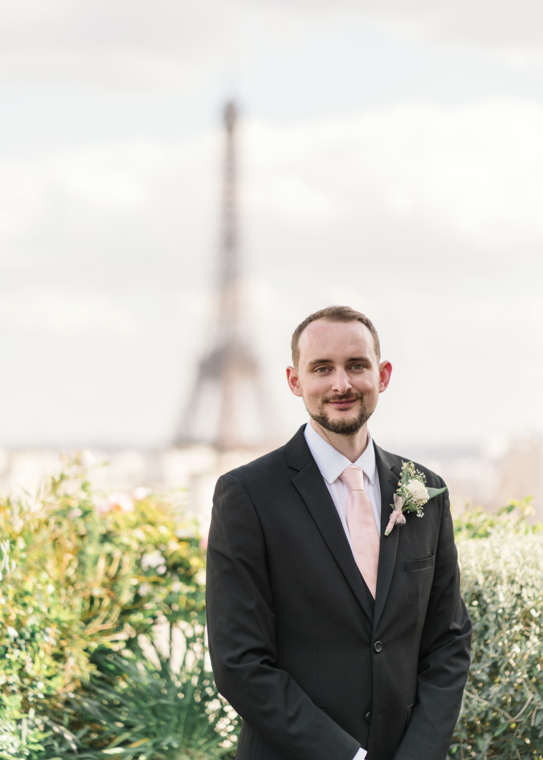 groom poses in front of eiffel tower on his wedding day