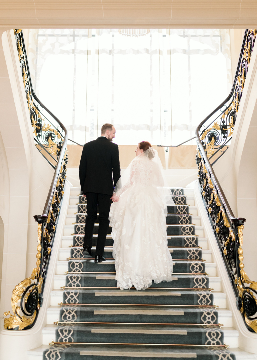 bride and groom ascend staircase at peninsula hotel paris