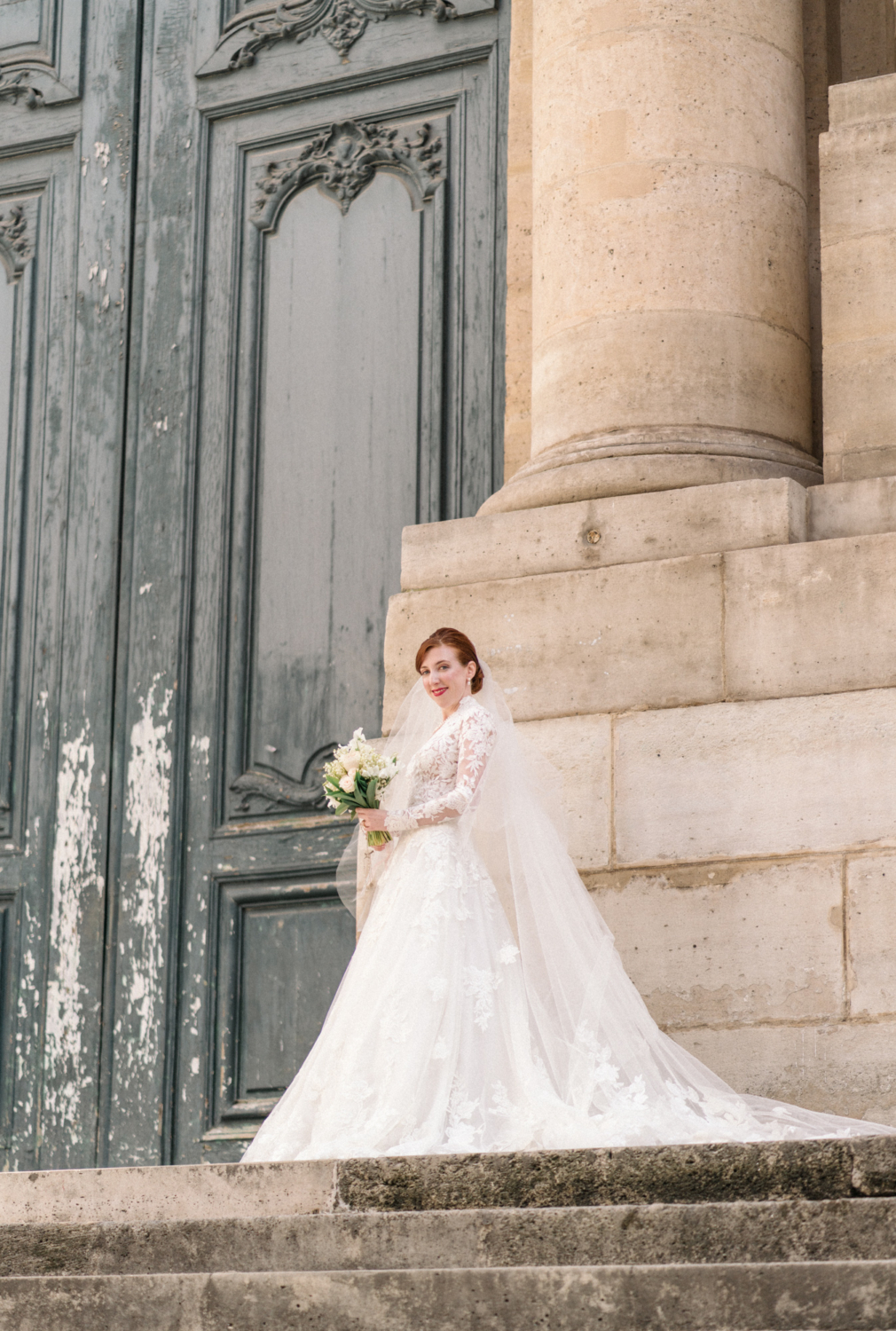 bride poses on staircase of church of saint roch in paris