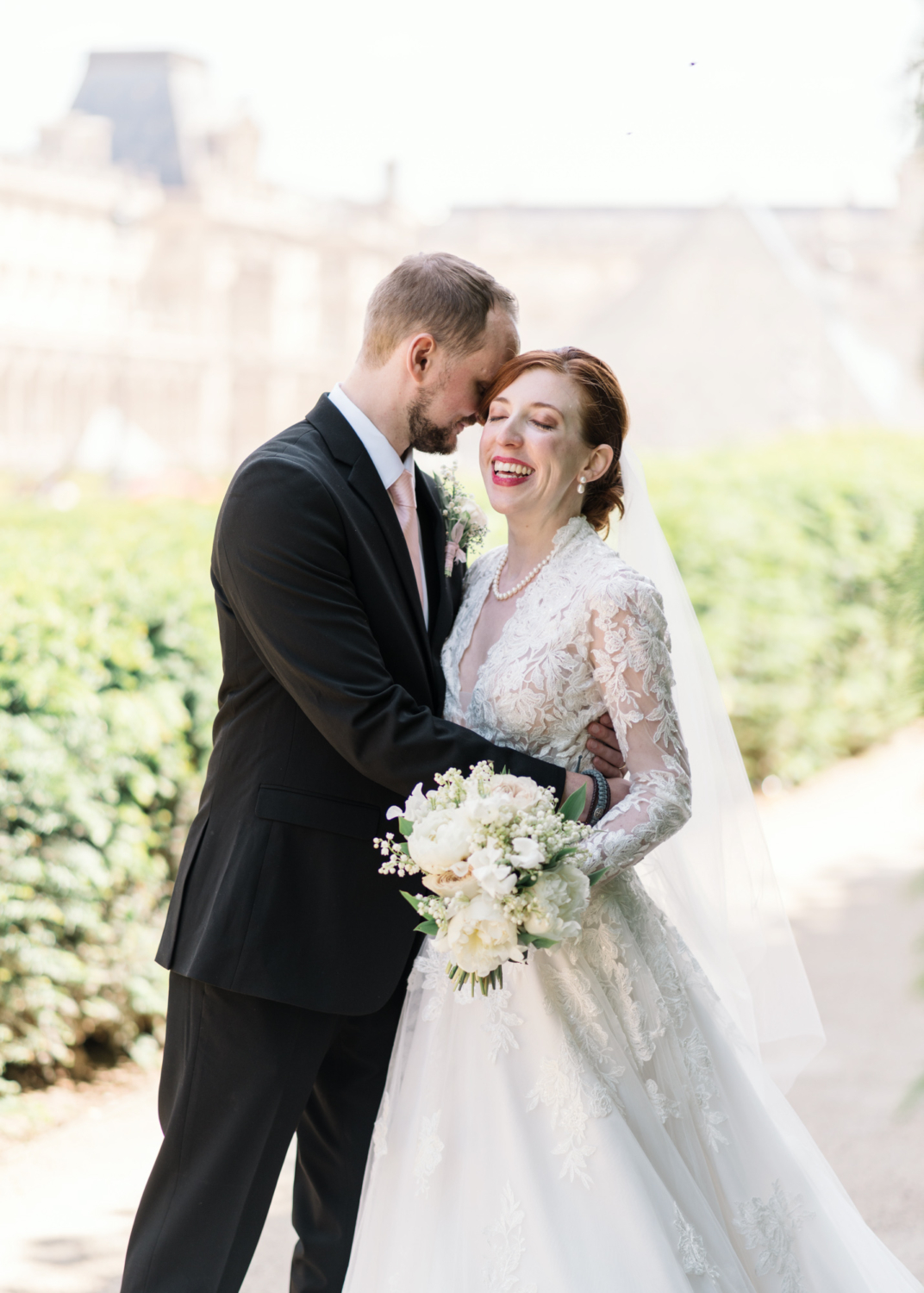 bride smiles as she poses with groom in paris
